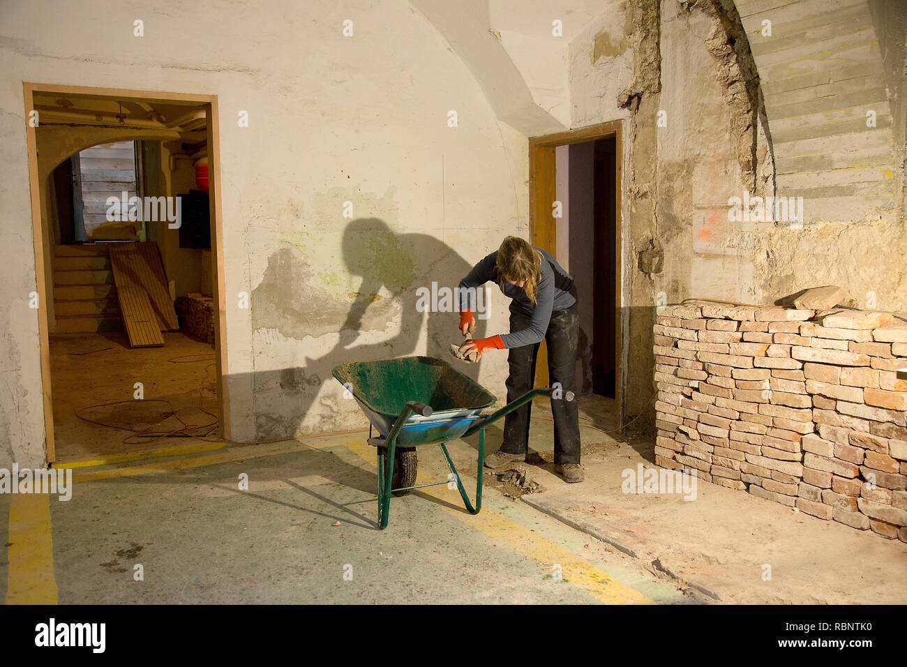 Donna carichi di materiale di scarto con un cucchiaio in muratura in una carriola Foto Stock