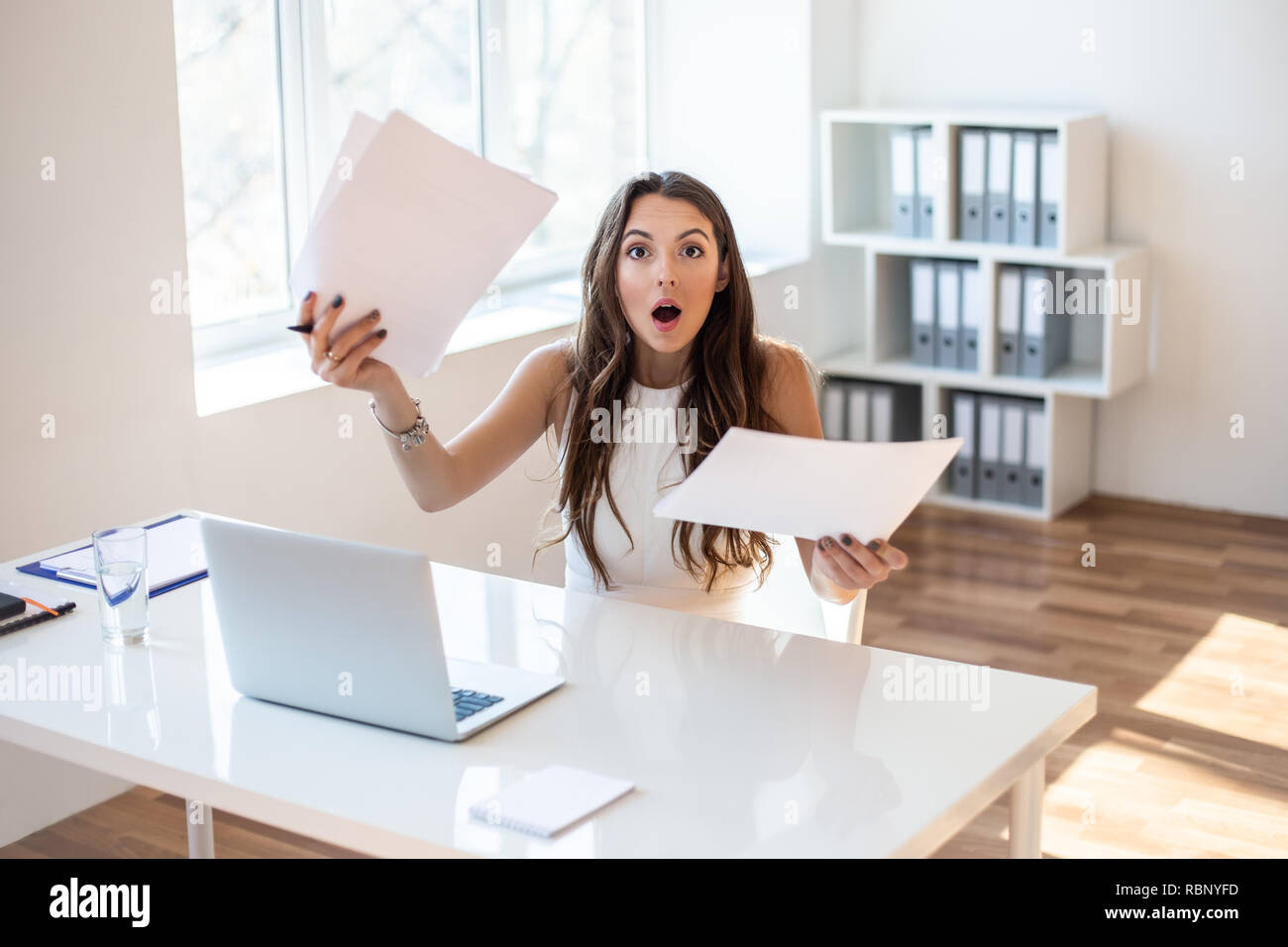 Imprenditrice sorpreso leggendo la carta in luoghi di lavoro in ufficio. Business donna frustrati e ha sottolineato con nuovo contratto Foto Stock