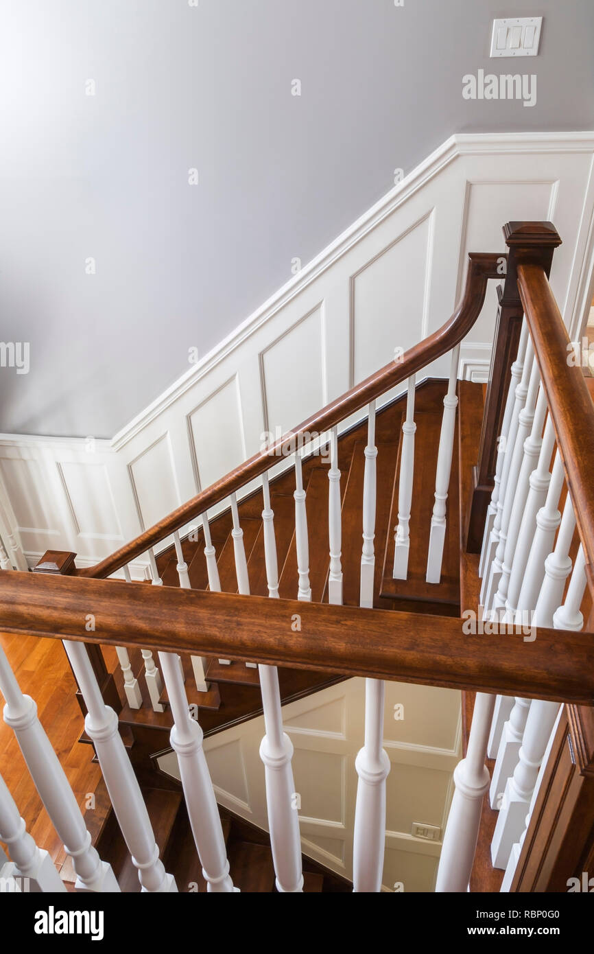 Scala e ringhiere in legno di ciliegio con mandrini bianchi al piano  superiore all'interno di una casa in stile cottage contemporaneo Foto stock  - Alamy