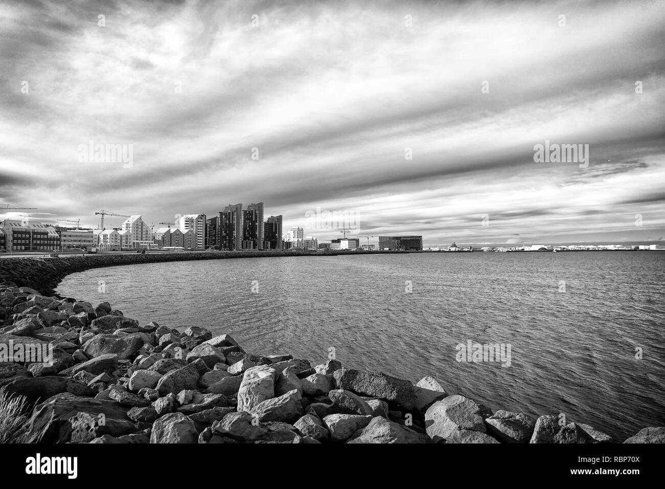 Seascape con pietra costa a Reykjavik, Islanda. Città edificio sul lato mare. Skyline sul cielo nuvoloso. Architettura e costruzione. Wanderlust o viaggi e avventura. Foto Stock