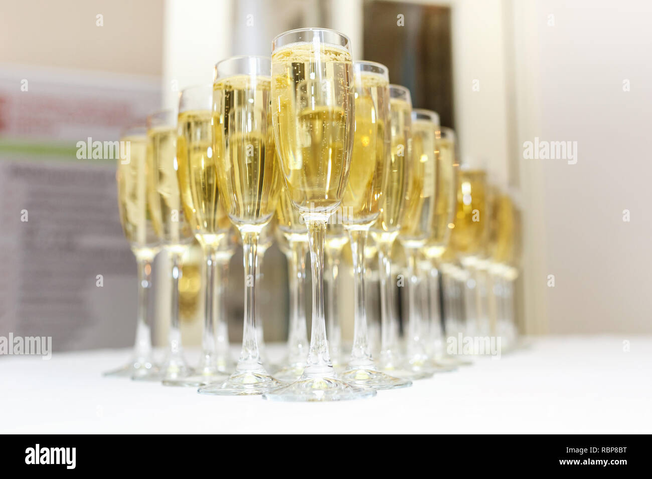 Sacco di offuscata occhiali con champagne sulla ricezione delle parti tabella su sfondo chiaro Foto Stock