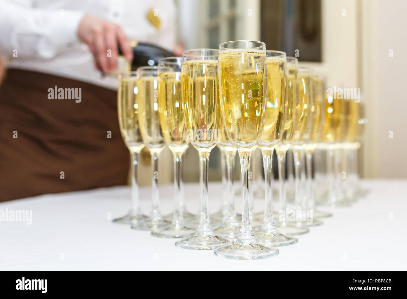 Sacco di offuscata occhiali con champagne sulla ricezione delle parti tabella su sfondo chiaro Foto Stock