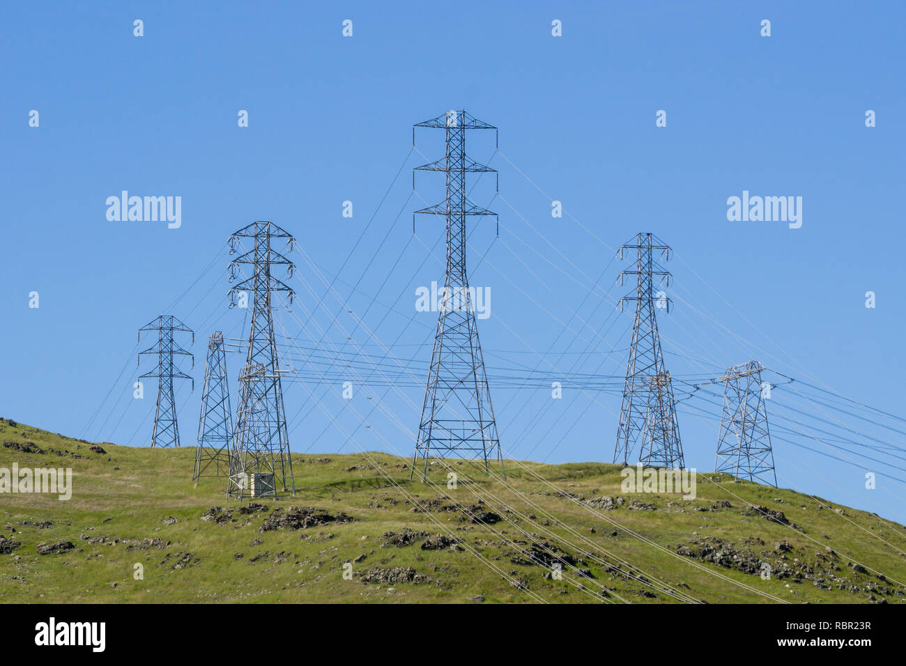 Di energia elettrica ad alta tensione torri su un cielo blu di sfondo, California Foto Stock