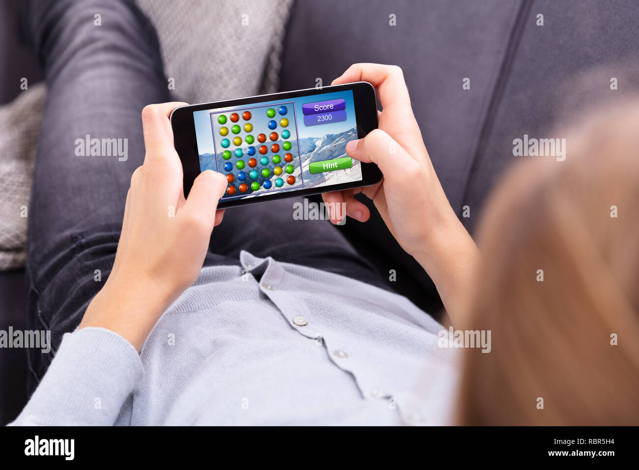 Close-up di una mano della ragazza un gioco sul telefono cellulare Foto Stock