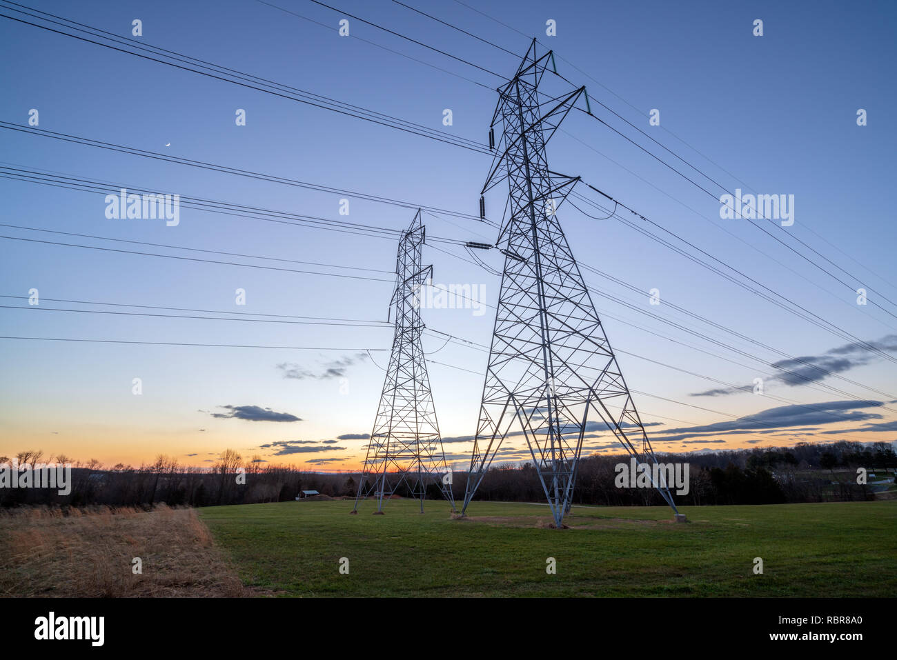 La distribuzione di energia elettrica le torri e i fili al crepuscolo Foto Stock