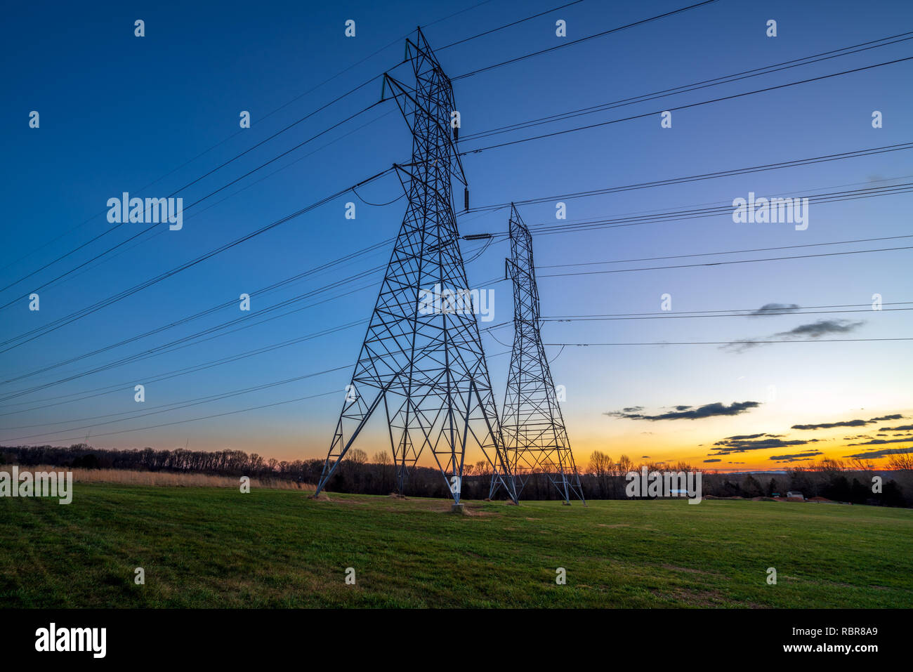 La distribuzione di energia elettrica le torri e i fili al crepuscolo Foto Stock