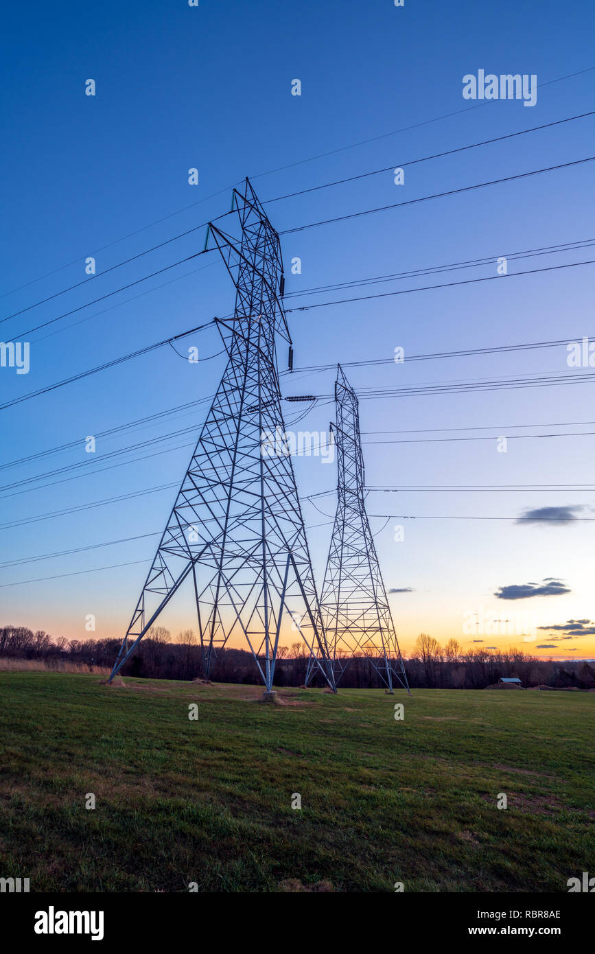 La distribuzione di energia elettrica le torri e i fili al crepuscolo Foto Stock