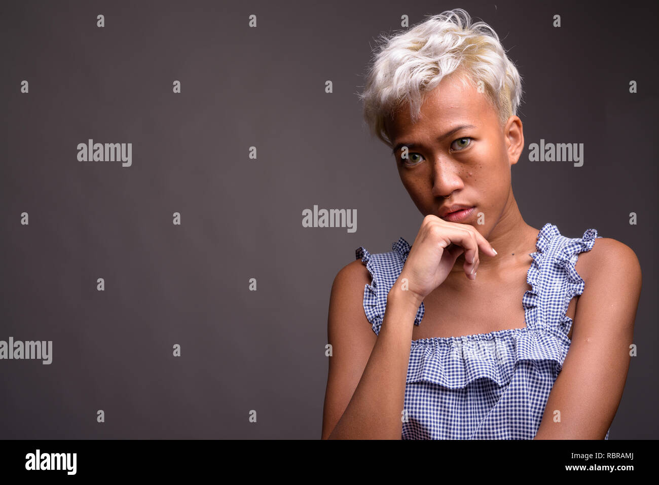 Giovane ribelle di bella donna con capelli corti contro il grigio ba Foto Stock