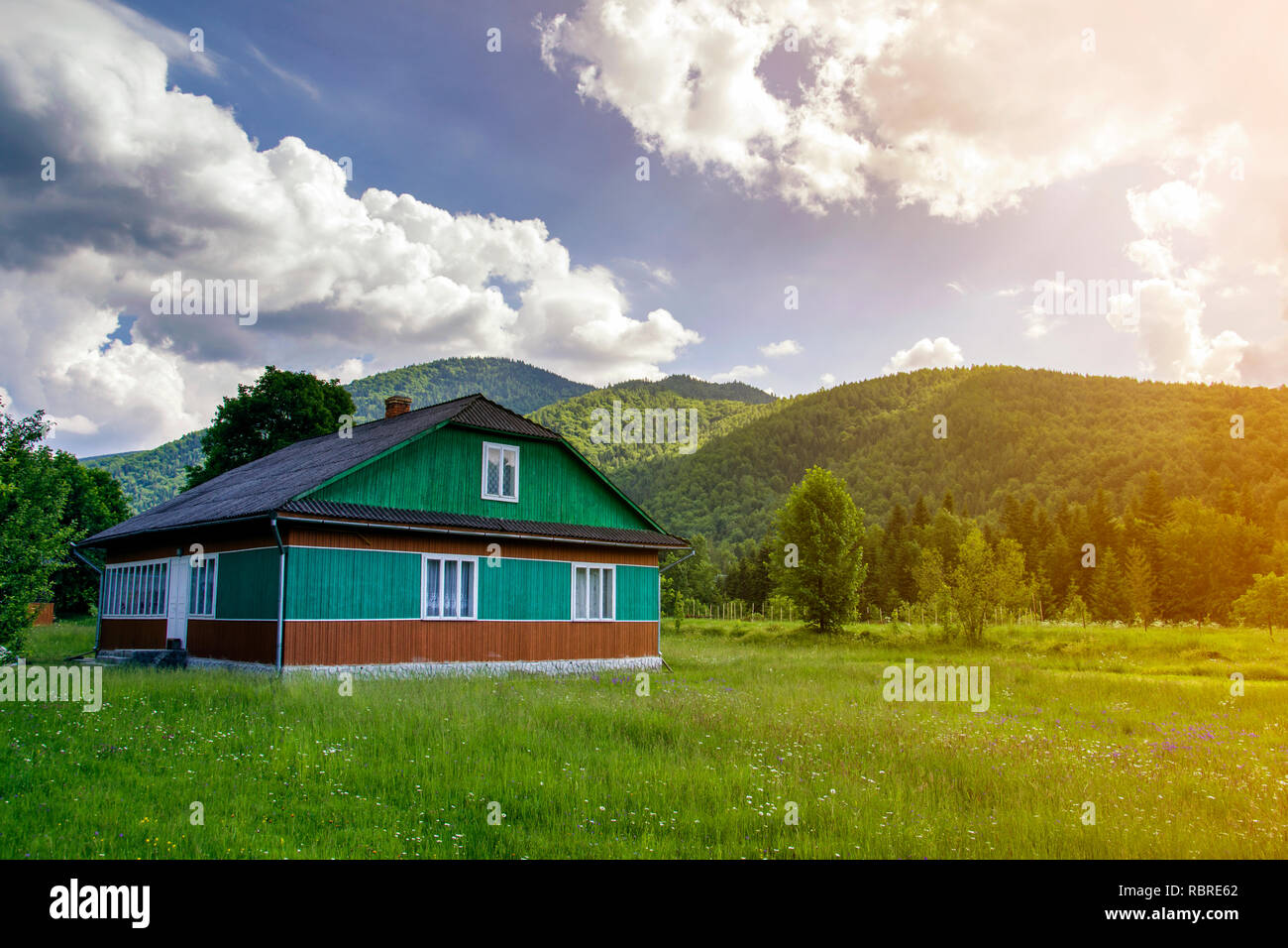 Bella rurali paesaggio estivo sulla luminosa giornata di sole. Illuminata da sole due belle di legno tradizionali case di Ucraina, residenziale e abbandonato sulla collina erbosa Foto Stock