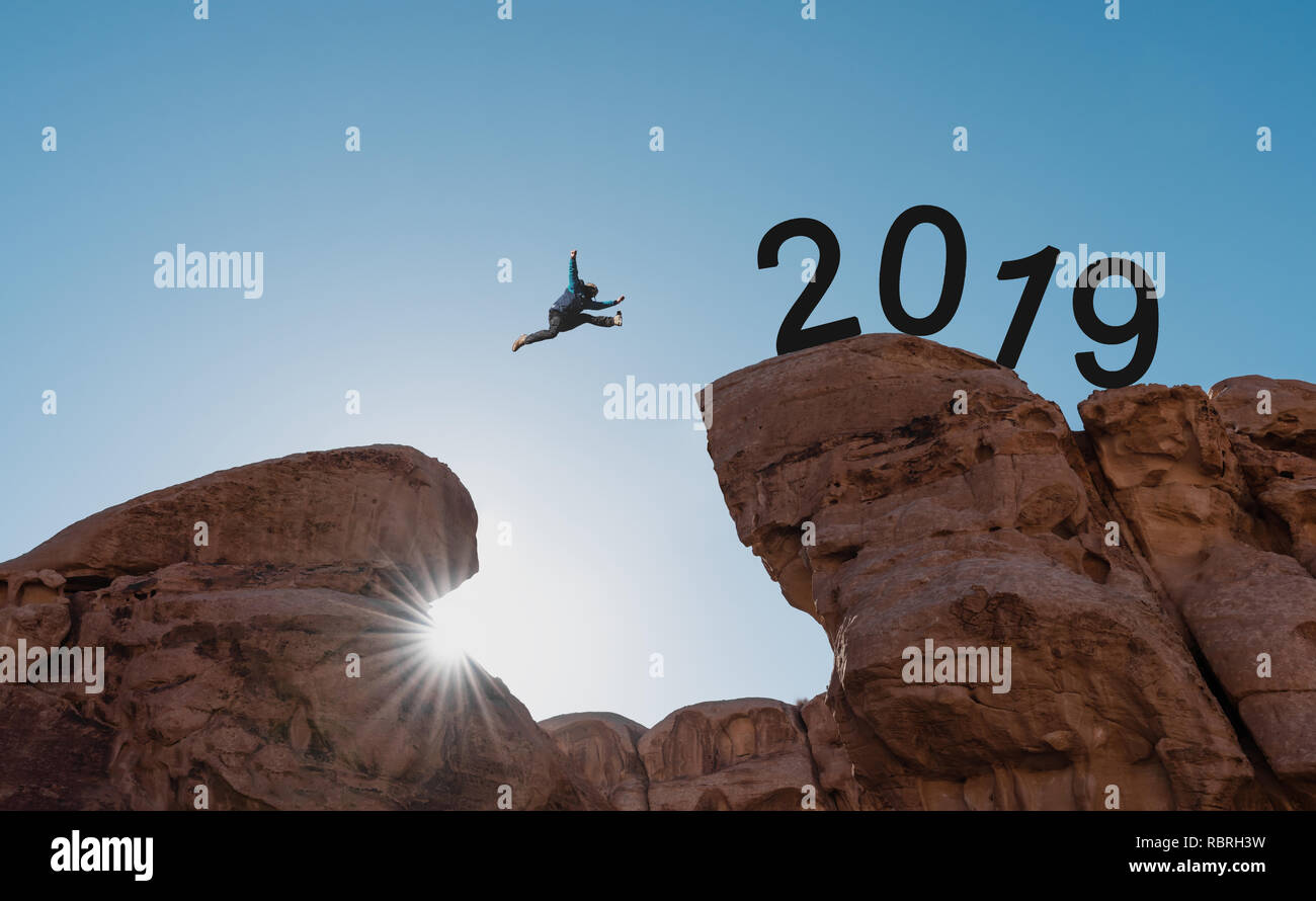 Anno nuovo concetto, silhouette di un uomo di saltare attraverso cliff a 2019 Foto Stock