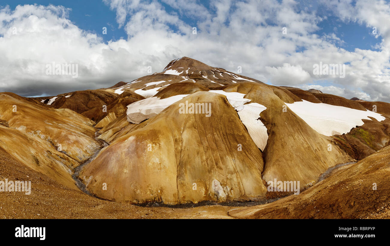 Panorama di una grande pietra scura del paesaggio in background con una gamma di montagna incandescente nella luce della sera - Location: Islanda, altopiani, Bergland Foto Stock
