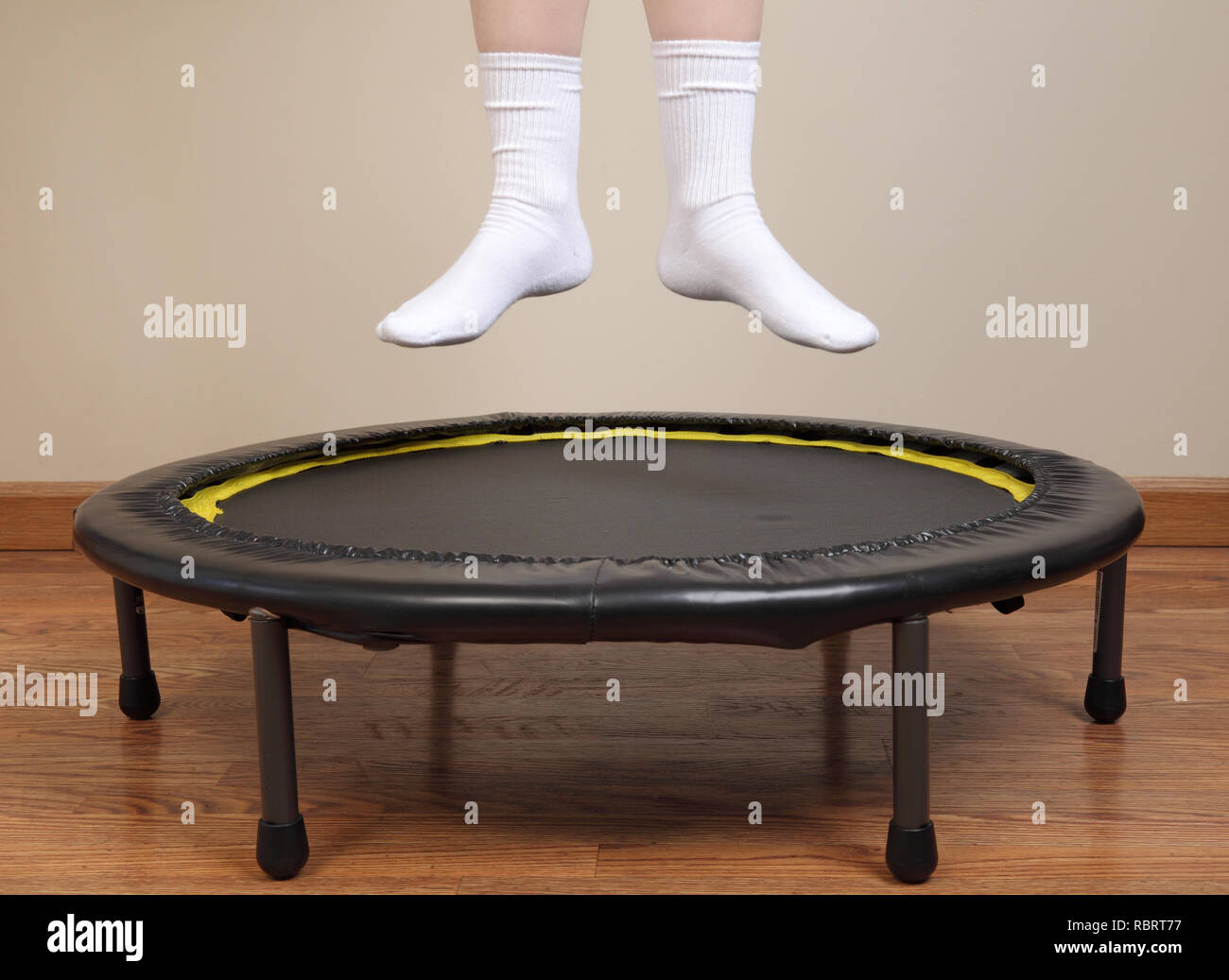 Donna di saltare sul trampolino di piccole dimensioni che mostra i piedi e le gambe inferiori solo Foto Stock