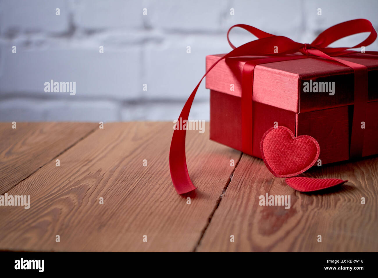 Regalo o presente scatola con fiocco rosso e nastro glitter cuore su sfondo  rustico per il