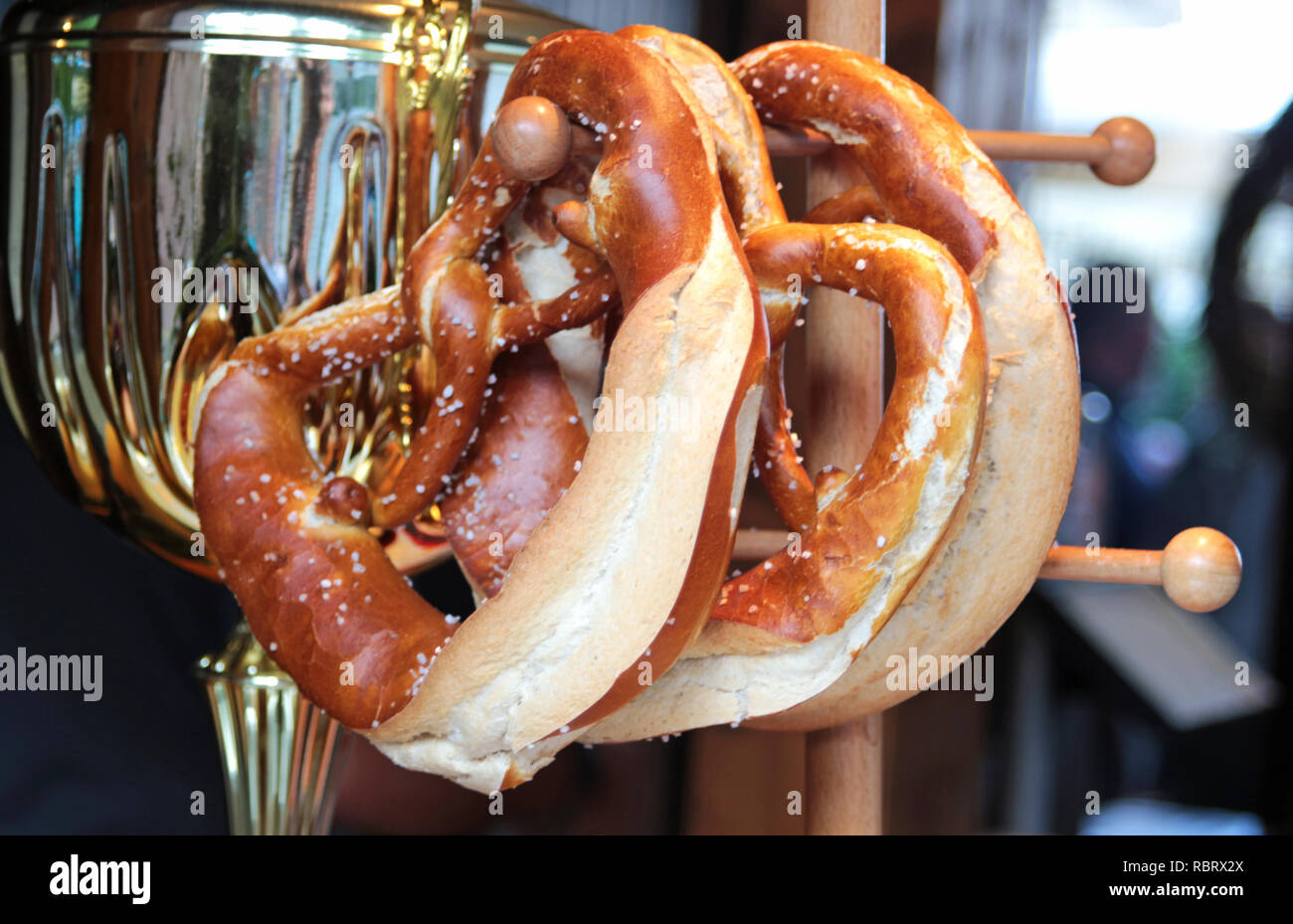 Close-up di freschi di forno Pretzel bavarese appeso su un rack di legno con un metallo salsiccia pot in retro Foto Stock