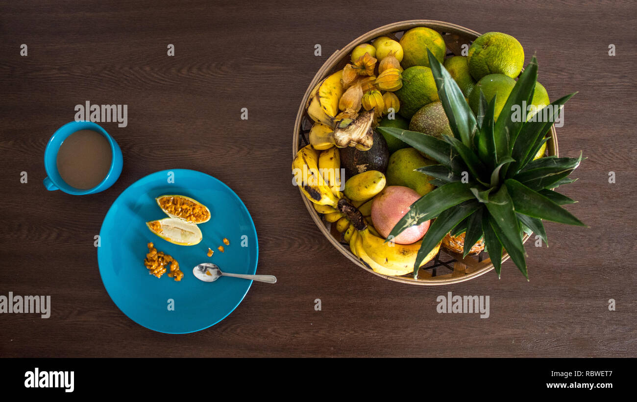 Una foto di una sana colazione vegana costituito da una tazza di caffè e una banana il frutto della passione e altri deliziosi frutti tropicali. Foto Stock