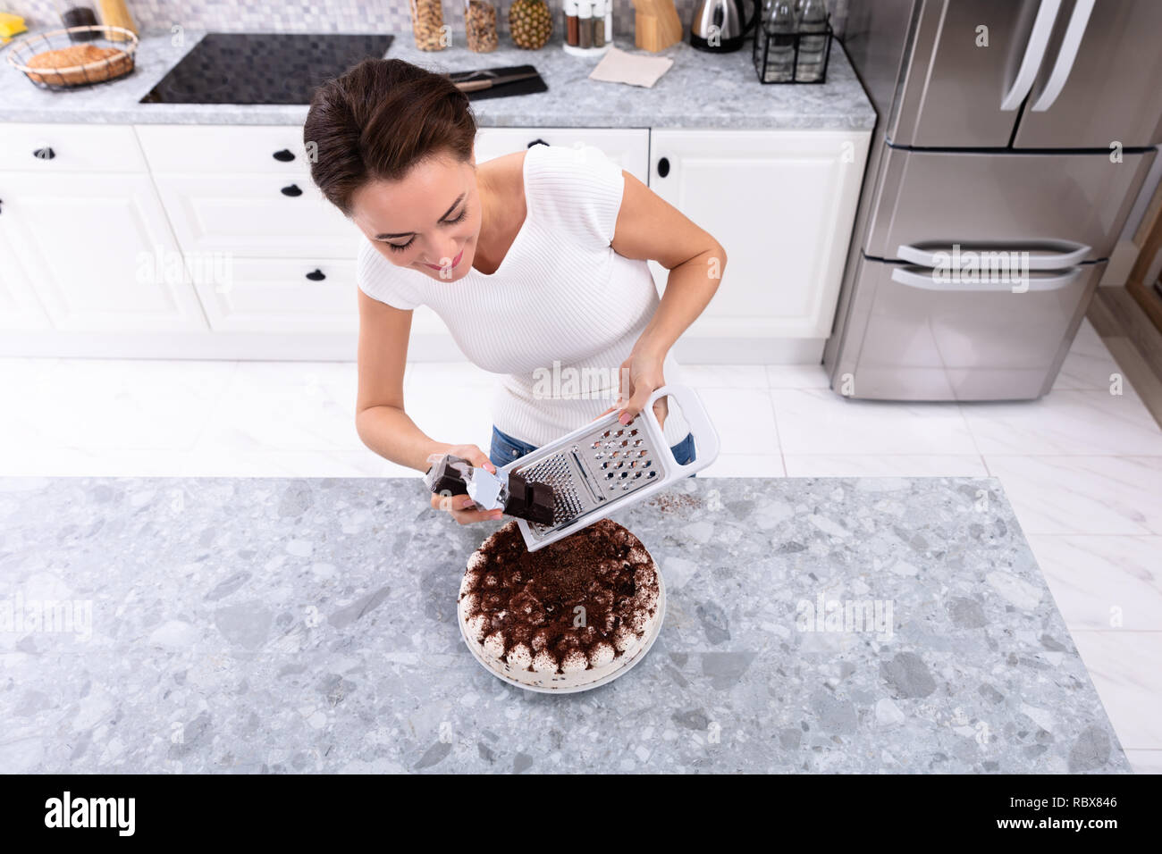 Ritratto di un sorridente giovane donna cioccolato reticolo sulla torta Foto Stock