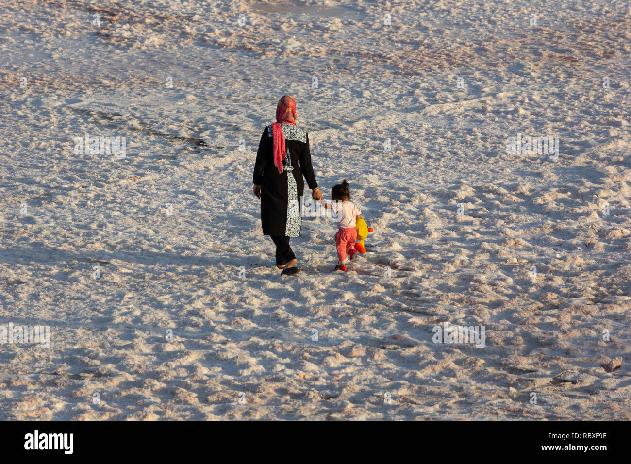 Una donna sta camminando con il suo bambino sulla distesa di sale del lago di Urmia, West Azerbaijan provincia, Iran Foto Stock