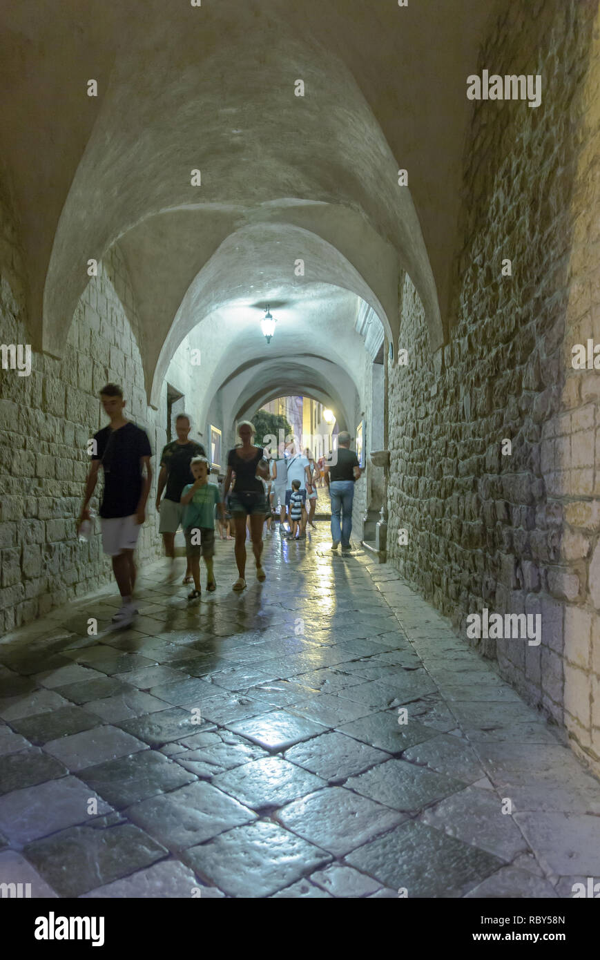 Turisti di passaggio attraverso le strette strade di pietra archi & via di passaggio nella storica città vecchia di Krk Quarnero, Croazia Foto Stock