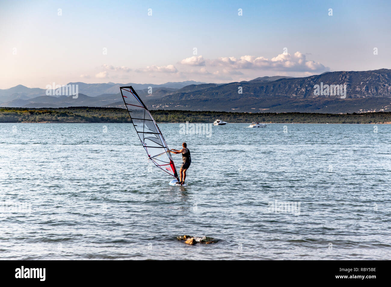Windsurf in Soline Bay sull'Isola di Krk, Croazia. Alpi Dinariche visibile sulla baia in background. Foto Stock
