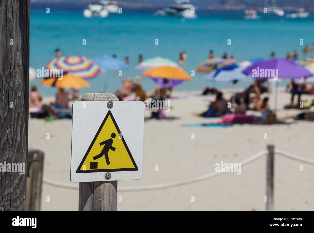 Discesa segno di avvertimento , caduta del bordo triangolo giallo segno sulla spiaggia Foto Stock