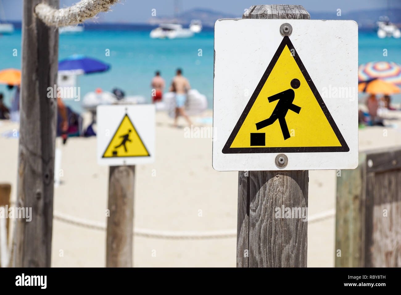 Discesa segno di avvertimento , caduta del bordo triangolo giallo segno sulla spiaggia Foto Stock