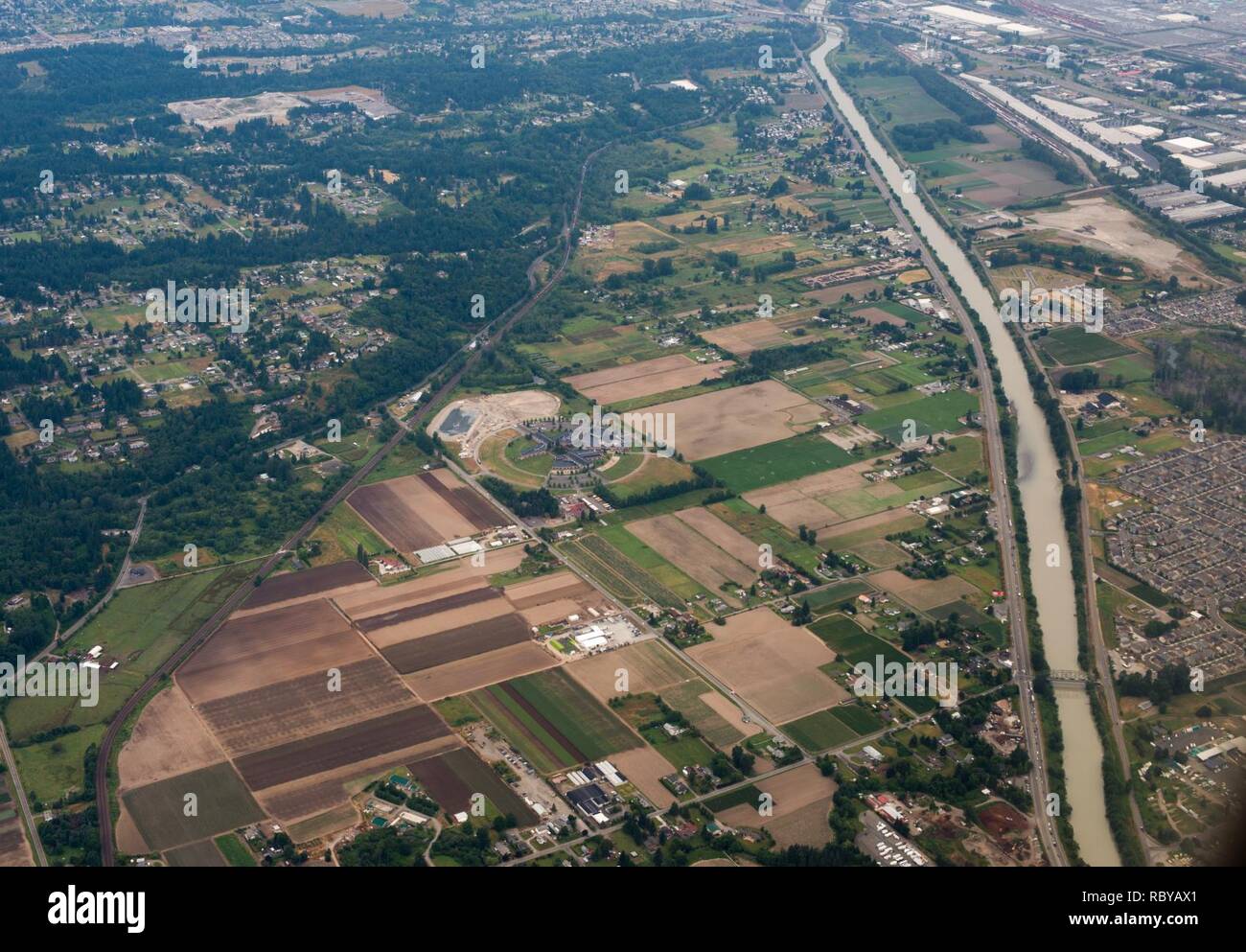 Puyallup, WA. 5625 52nd Street East. Amministrazione della scuola è struttura circolare in centro, circondato da aziende agricole, con l'Puyallup fiume che scorre dall'alto verso il basso sul lato destro, una ferrovia sul lato sinistro e quartieri residenziali a sinistra e a destra. In basso a destra che attraversa il fiume Puyallup è George Milroy ponte (66Ave E). In alto a destra di edifici di grandi dimensioni sono visibili tra cui un FedEx World Service Center e magazzino diverse dimensioni sbocchi commerciali. Fotografia aerea della zona circostante Chief Leschi Amministrazione Scolastica. Foto Stock