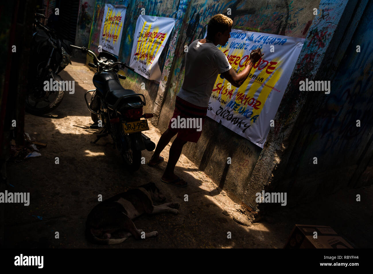 Un cartello colombiano pittore scrive con un pennello mentre si lavora sulla musica poster di partito nel segno atelier di pittura a Cartagena, Colombia. Foto Stock