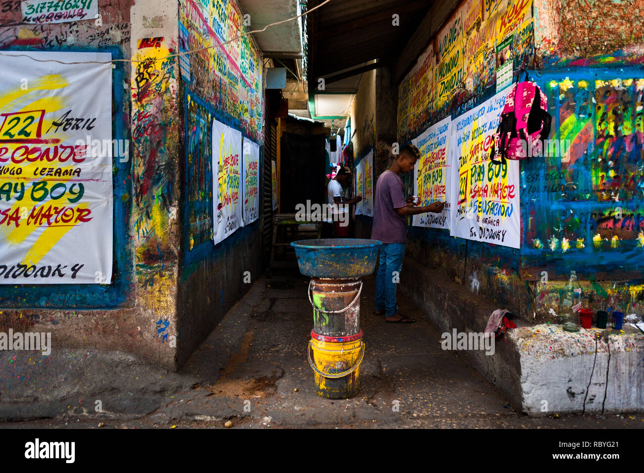 Cartello colombiano pittori scrivere con un pennello mentre si lavora sulla musica poster di partito nel segno atelier di pittura a Cartagena, Colombia. Foto Stock