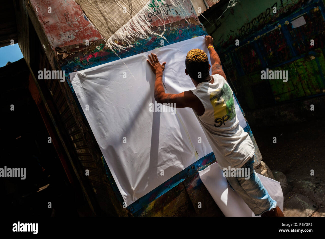 Un cartello colombiano pittore bastoni una carta bianca sulla parete nel segno atelier di pittura a Cartagena, Colombia. Foto Stock