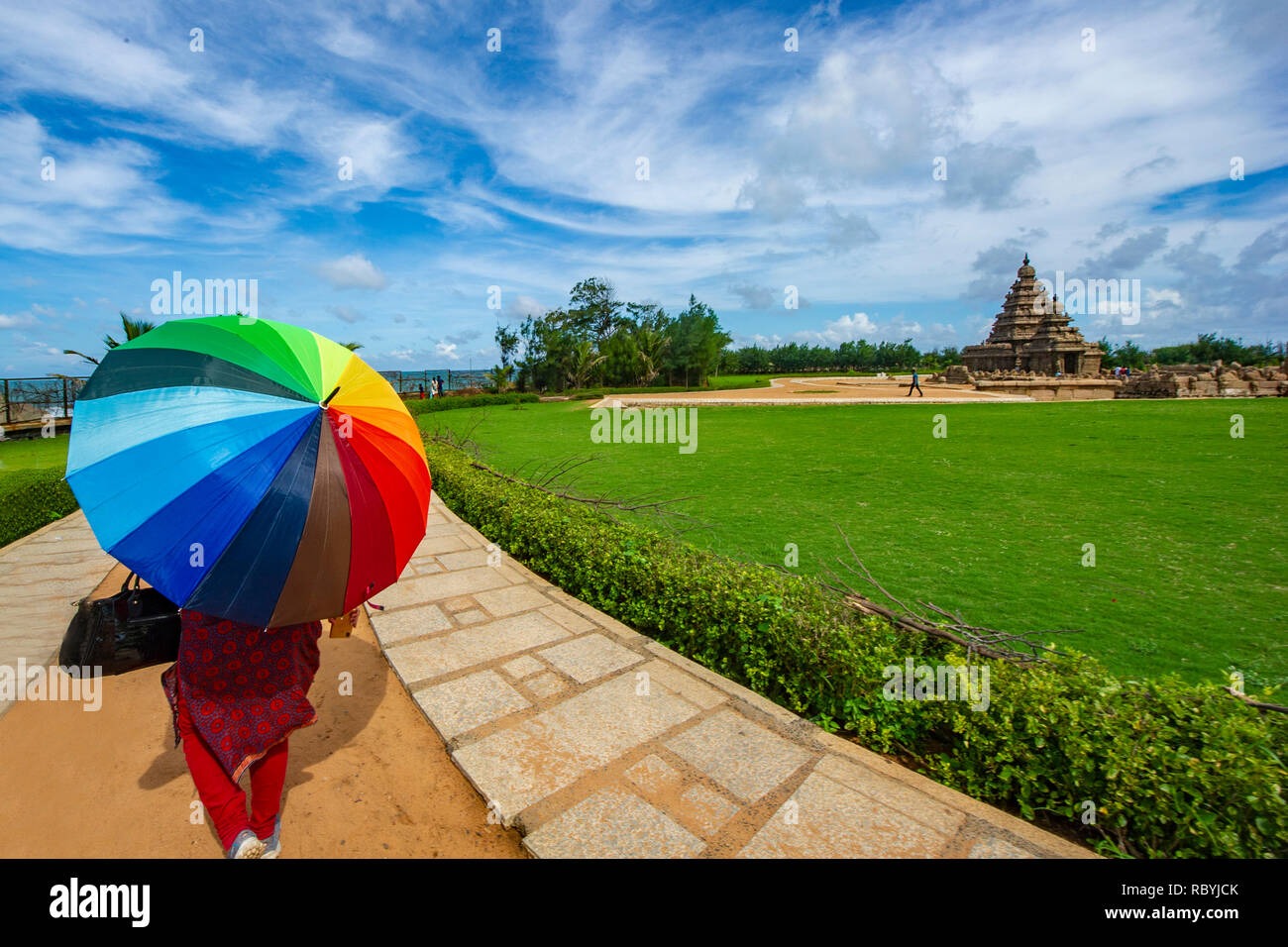 Una donna con un vivacemente colorato ombrellone a monumenti di Mahabalipuram vicino a Chennai, India Foto Stock