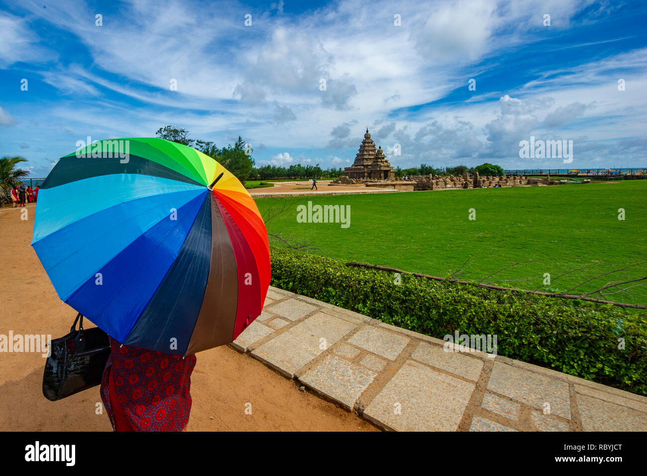 Una donna con un vivacemente colorato ombrellone a monumenti di Mahabalipuram vicino a Chennai, India Foto Stock