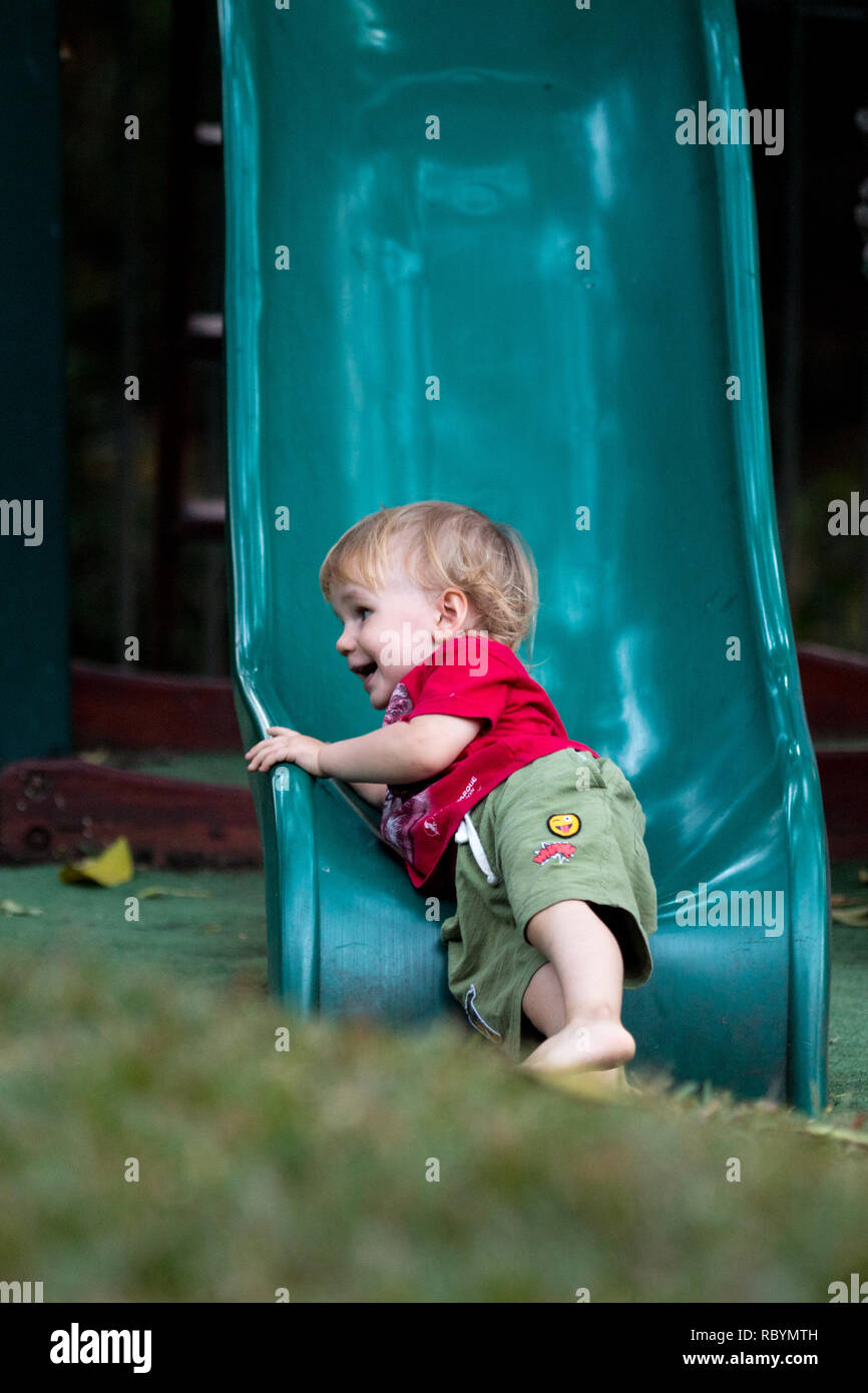 Una foto di un giovane ragazzo di felice lo scorrimento verso il basso un parco giochi slitta Foto Stock