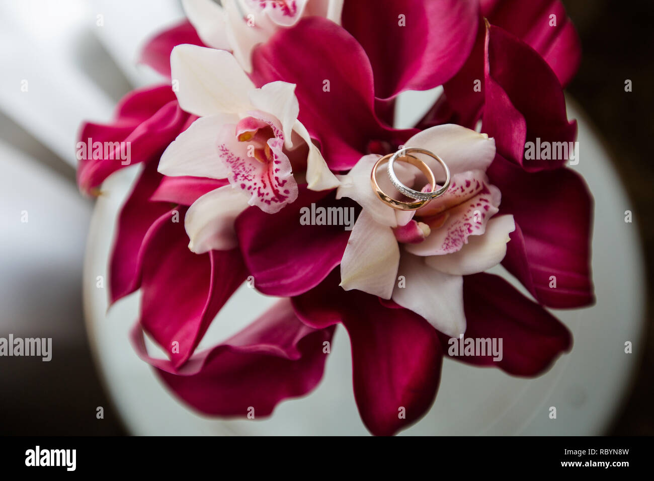 Una coppia di anelli di nozze su un bouquet di fiori rossi, close up shot Foto Stock