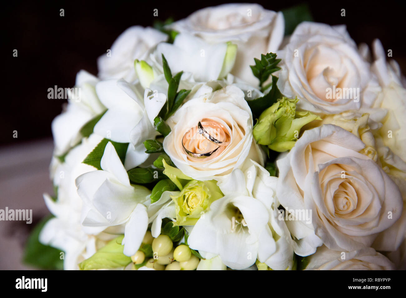 Una coppia di anelli di nozze su un bouquet di fiori bianchi, close up shot Foto Stock