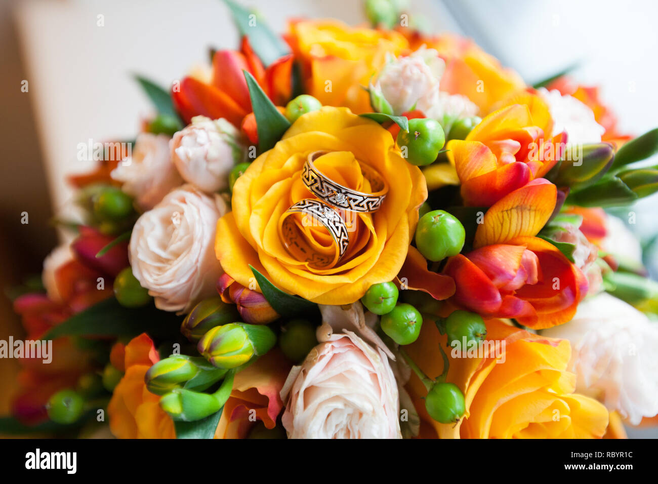 Una coppia di nozze anelli in oro su un bouquet di fiori colorati, close up shot Foto Stock