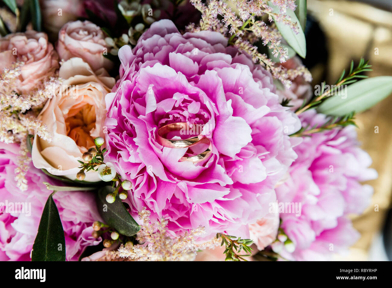 Una coppia di nozze anelli in oro su un bouquet di fiori colorati, close up shot Foto Stock