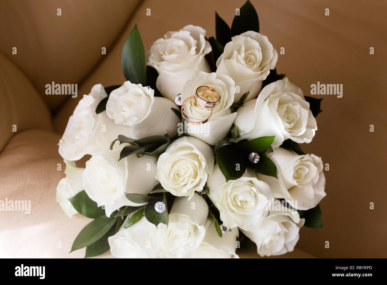 Una coppia di anelli di nozze su un bouquet di rose bianche, close up shot Foto Stock