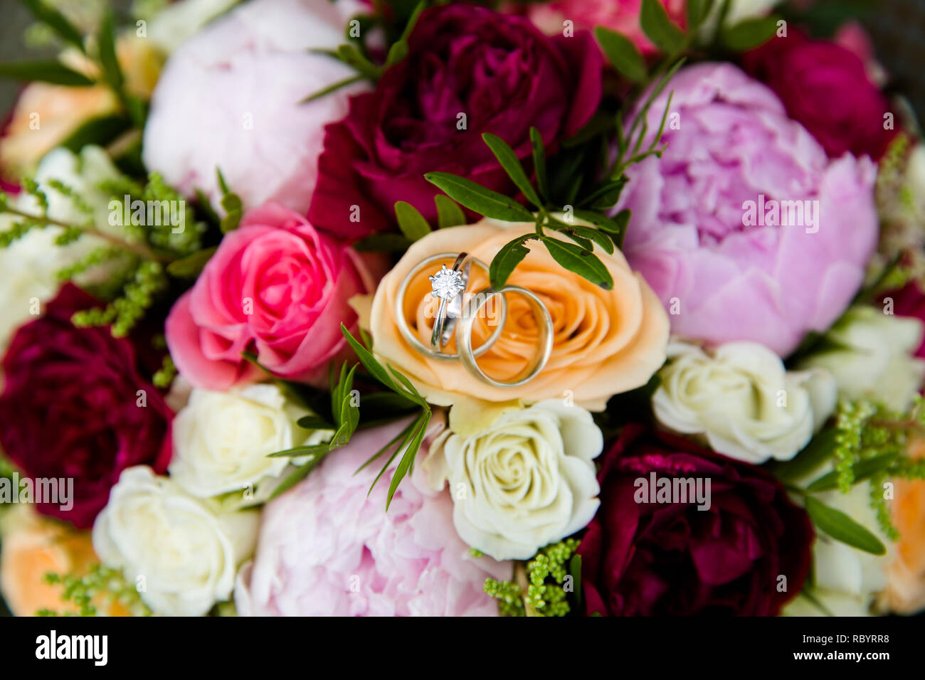 Una coppia di nozze anelli in oro su un bouquet di fiori colorati, close up shot Foto Stock