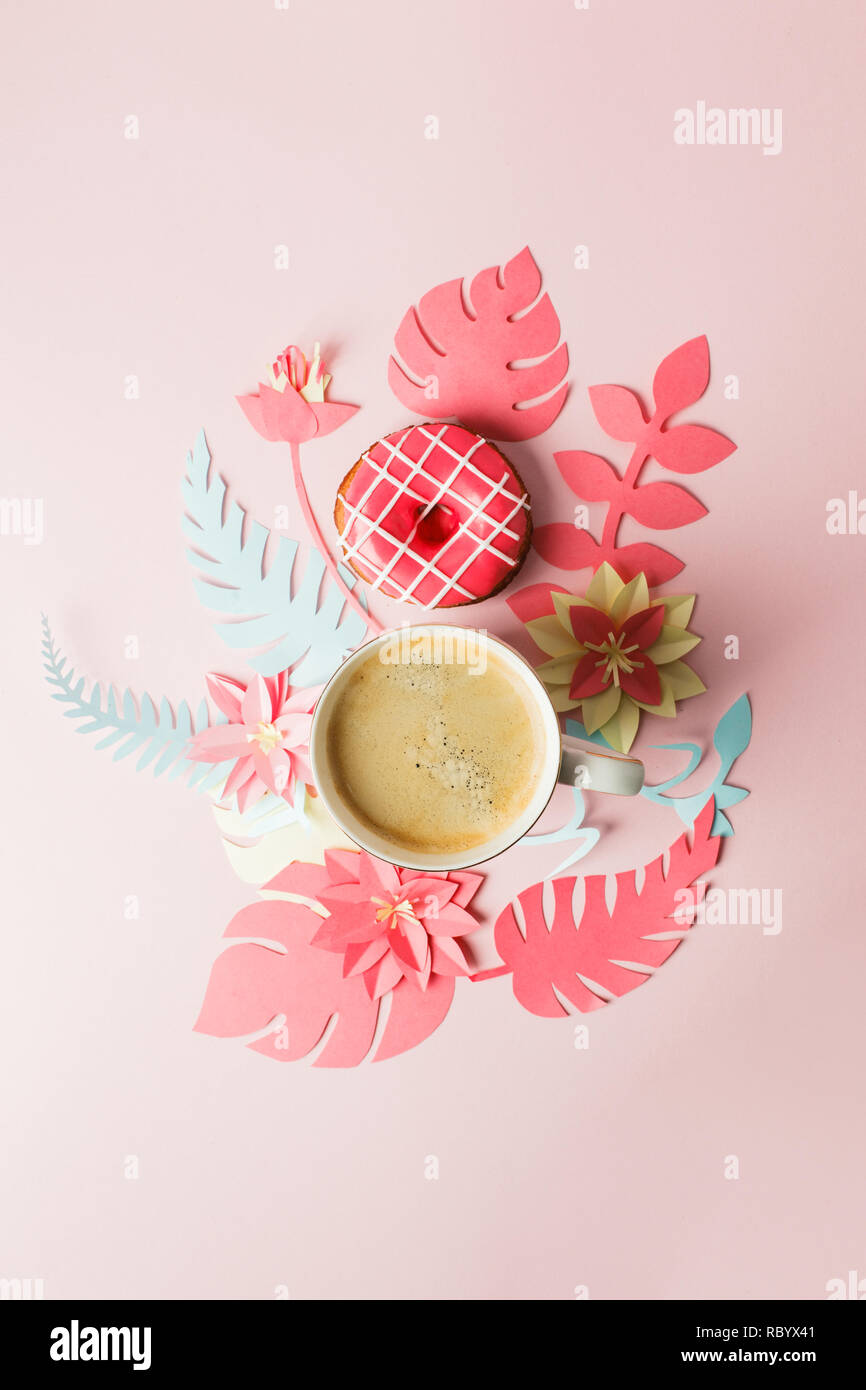 Vista da sopra con tazza di caffè, donut e moderno artigianato origami fiori di carta copia spazio. La donna il giorno 8 marzo. sfondo rosa. Donna e stilis Foto Stock