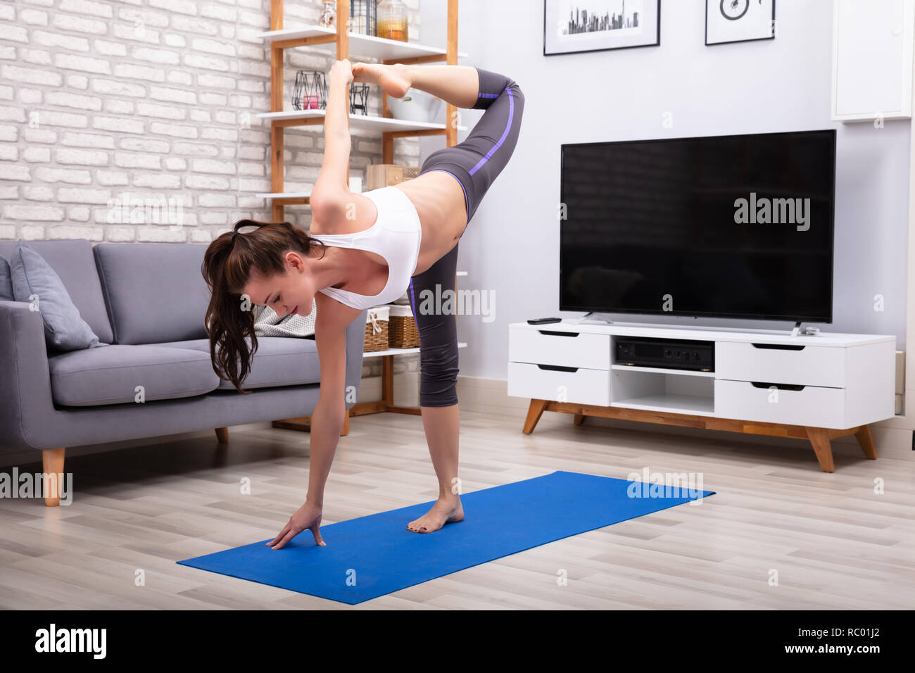 Flessibile di giovane donna a praticare Yoga su Blu esercizio Mat Foto Stock