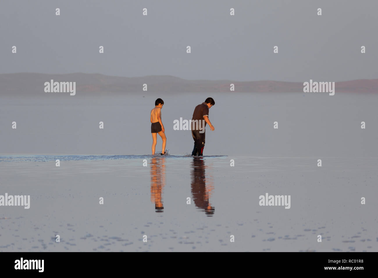 Un uomo cammina con il suo figlio nella distesa di sale del lago di Urmia, West Azerbaijan provincia, Iran Foto Stock