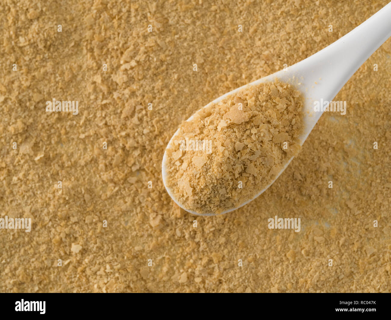 Il lievito nutrizionale dello sfondo. Nutrizionali di lievito inattivo in bianco cucchiaio. Copia dello spazio. Vista dall'alto. Il lievito nutrizionale è vegetariano super con sapore di formaggio, per una sana alimentazione Foto Stock