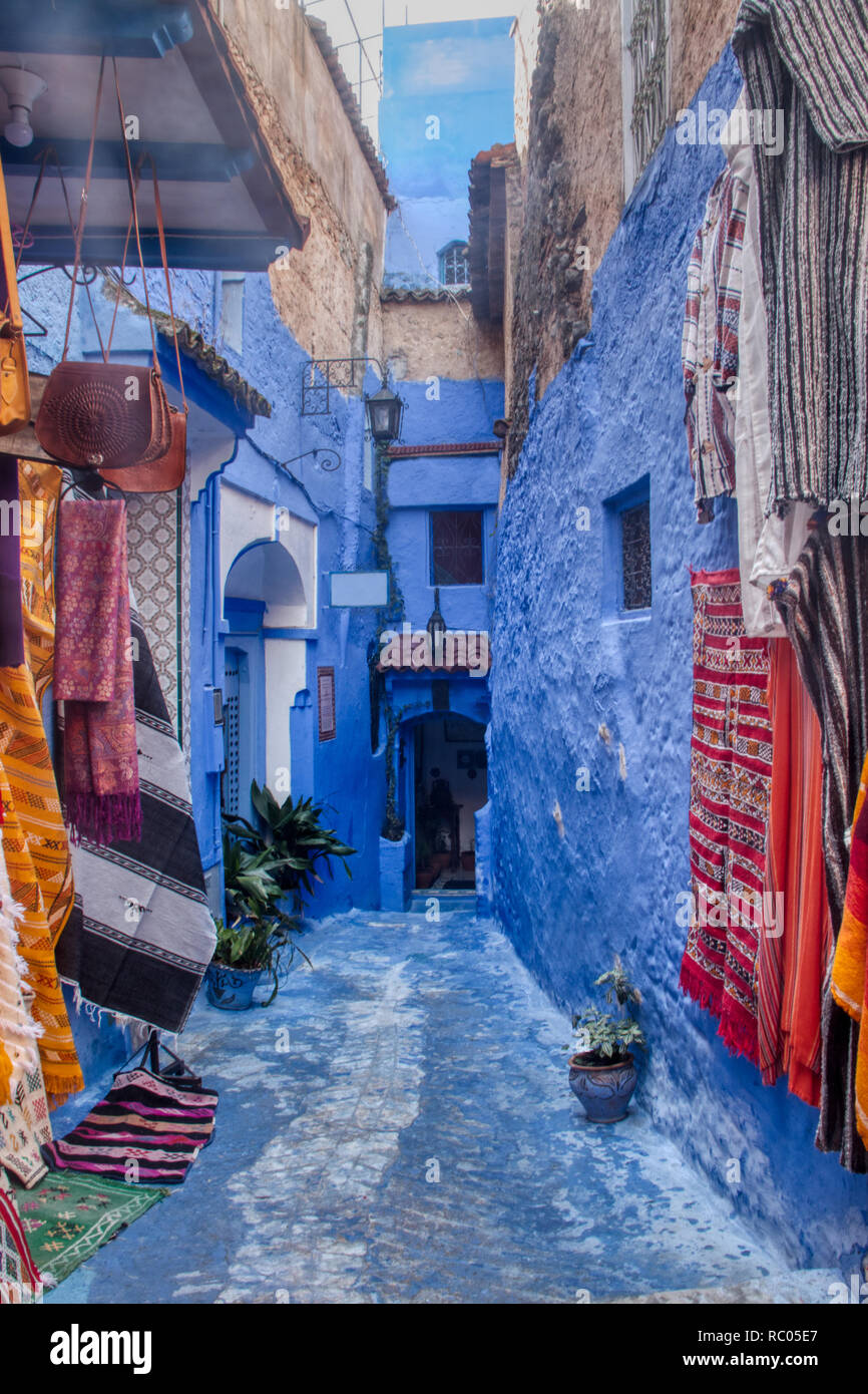 Strada tipica della Medina di Chefchaouen con piccoli negozi di souvenir che espongono i propri prodotti su strada. In Marocco, Africa del Nord Foto Stock