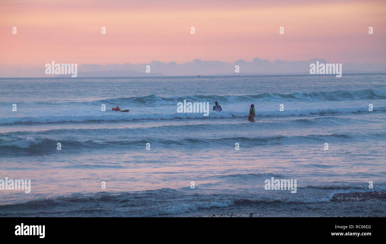 Una foto di persone godere il mare durante un bel colore arancione tramonto a Jaco Beach, Costa Rica Foto Stock