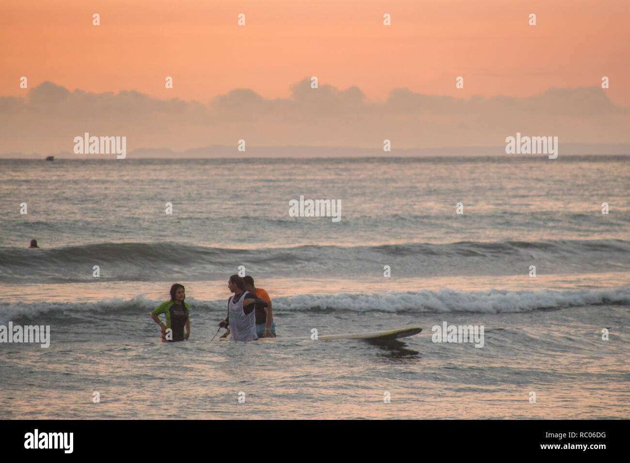 Una foto di persone godere il mare durante un bel colore arancione tramonto a Jaco Beach, Costa Rica Foto Stock