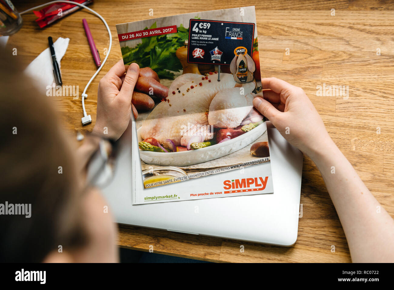 Parigi, Francia - 26 APR 2017: Donna lettura semplicemente Auchan brochure newsletter giornale in primo piano prezzi sconto per cibo, carne e bevande Foto Stock