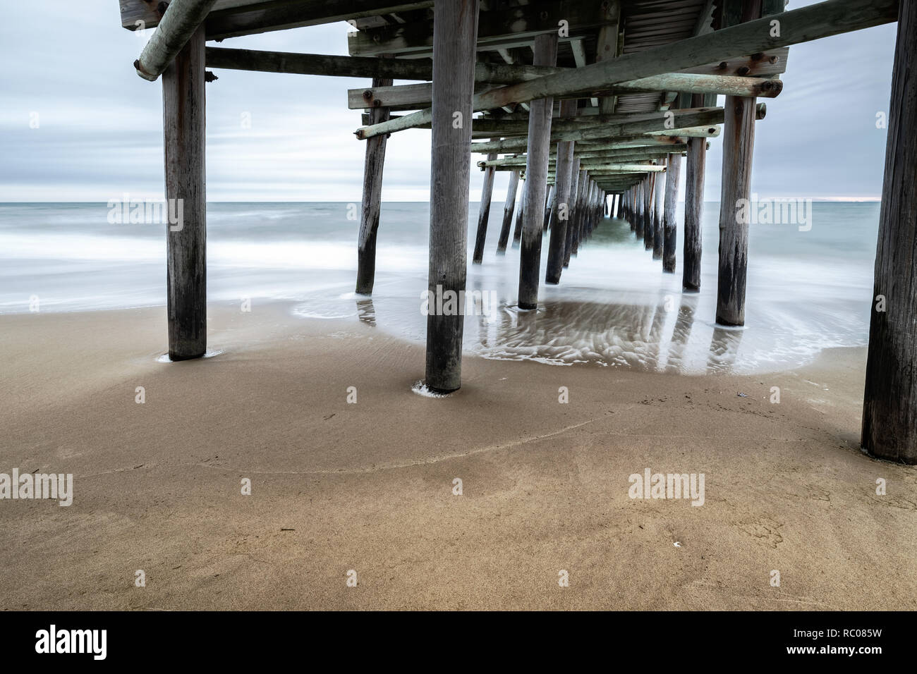 Come il sole sorge dietro la pesca Sandbridge Pier, onde crash - sotto-temi: prospettica, pace lunga esposizione, Otturatore lento, misty Foto Stock