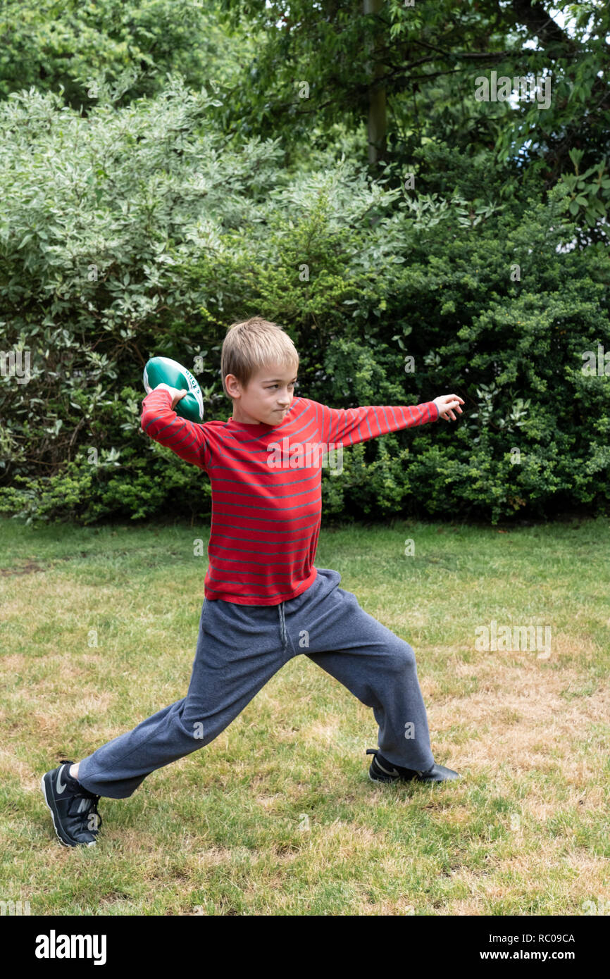 Dieci anni di vecchio ragazzo gettare un calcio nel suo cortile. (MR) Foto Stock