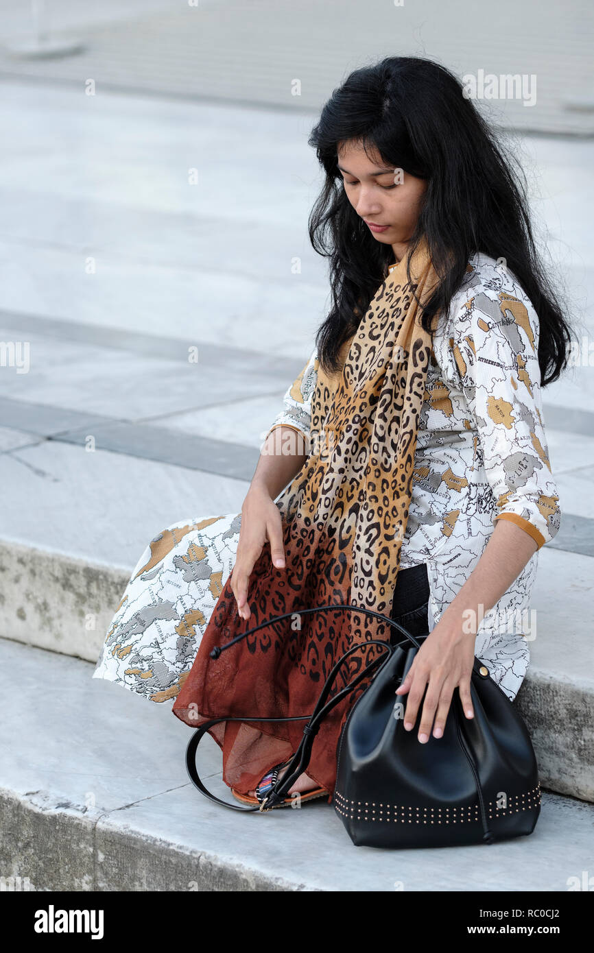 Turista femminile da Bangladash seduti sui gradini rilassanti in Piazza dei Miracoli a Pisa, Toscana, Italia, Europa Foto Stock