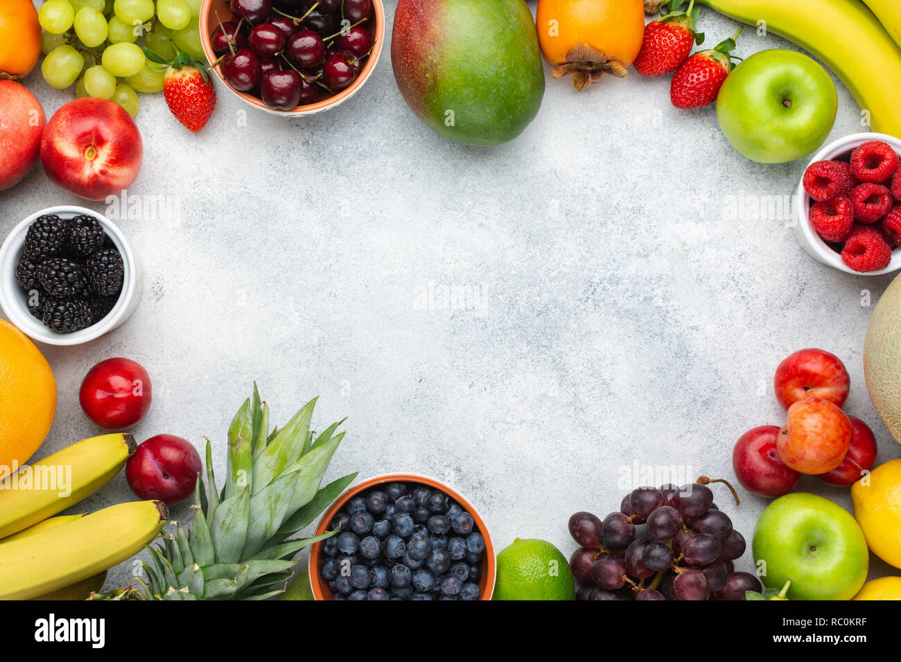 La frutta sana telaio dello sfondo, Fragole Lamponi arance Prugne Mele Kiwi uve mirtilli persimmon mango sul tavolo bianco Foto Stock